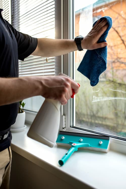 Hombre limpiando ventana con persiana veneciana